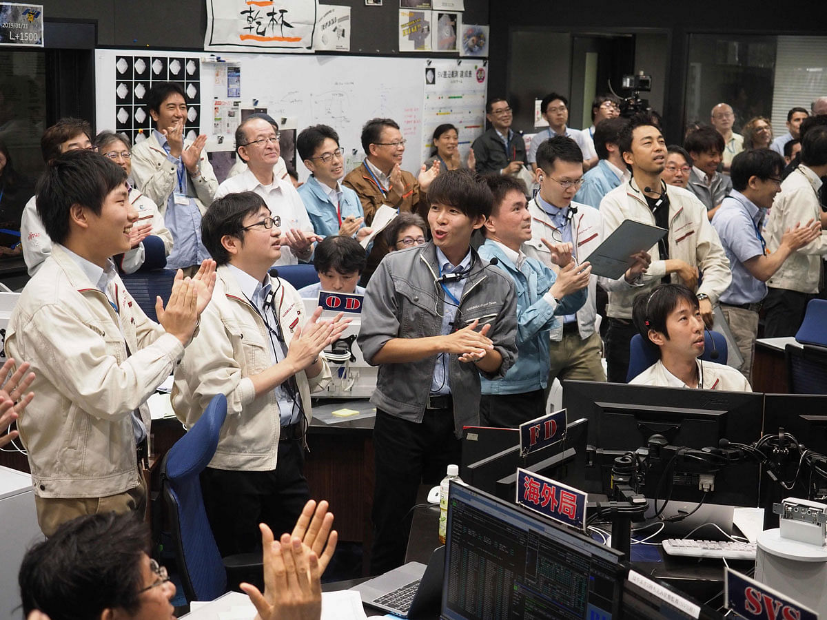 This handout photograph taken and released by the Institute of Space and Astronautical Science (ISAS) of Japan Aerospace Exploration Agency (JAXA) on 11 July 2019 shows researchers and employees celebrating after receiving confirmation of Hayabusa2`s touchdown on the asteroid Ryugu, at the mission control room in Sagamihara city, Kanagawa prefecture. Photo: AFP