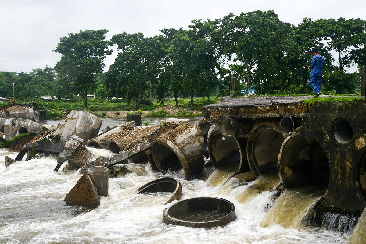 An Indian resident looks at the portion of a broken bridge connecting nearby villages, carried away by floods, at Taipu village some 25 kms from Siliguri on 12 July, 2019. Photo: AFP
