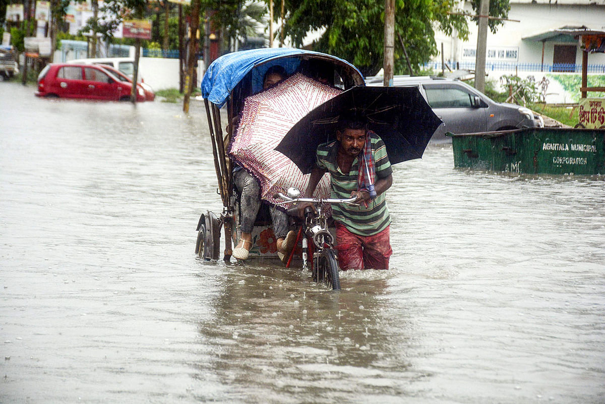 An Indian rickshaw puller carries a commuter through the flooded street during heavy rainfall in Agartala, the capital of northeastern state of Tripura, on 12 July, 2019. Photo: AFP