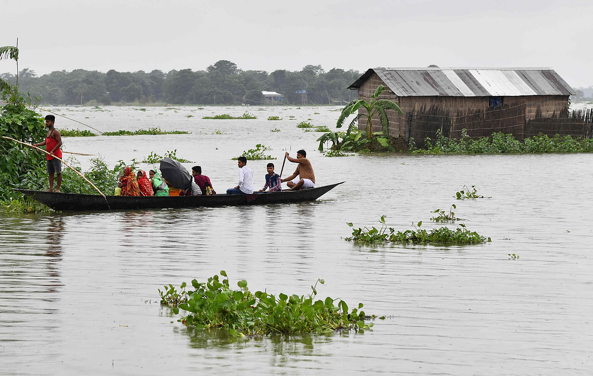 Indian villagers travel by boat through floodwaters near a partially submerged house in Balimukh village of Morigoan district in India`s northeastern state of Assam on 11 July 2019. Photo: AFP