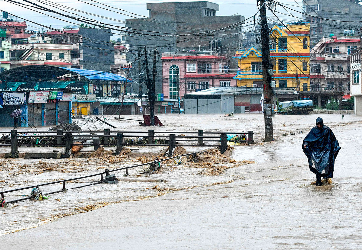 A Nepali resident walks through floodwaters after the Balkhu River overflowed following monsoon rains at the Kalanki area of Kathmandu on 12 July, 2019. Photo: AFP