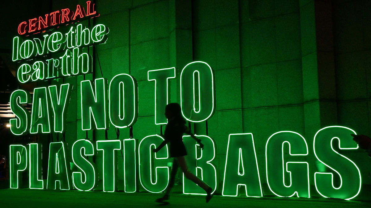 This photo taken on 12 July, 2019 shows a girl running in front of a sign promoting less use of plastic outside a mall in Bangkok. Photo: AFP
