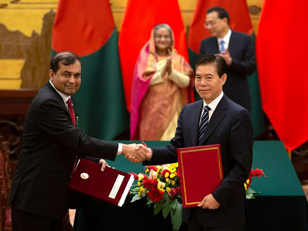 China commerce minister Zhong Shan (R) shakes hands with a Bangladeshi delegate as Bangladesh’s prime minister Sheikh Hasina (back-L) and Chinese premier Li Keqiang applaud during a signing ceremony at the Great Hall of the People in Beijing on 4 July 2019. AFP File Photo