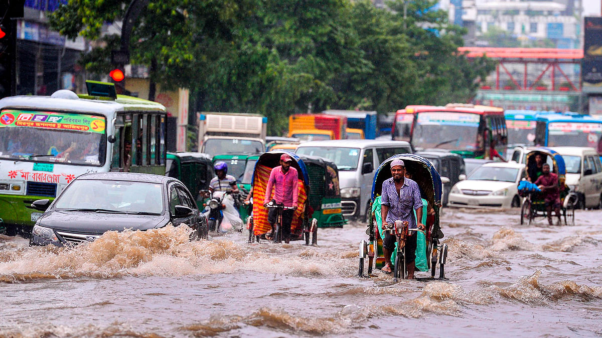 Bangladeshi rickshaw pullers make their way through heavy rainfall at a water-logged street during the monsoon season in Dhaka on 12 July 2019. Photo: AFP