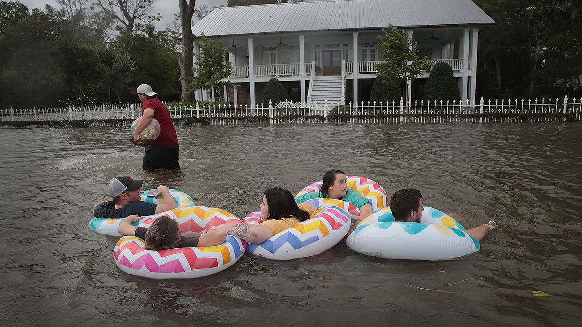 People float down Lakeshore Drive which is covered by water from Lake Pontchartrain after the area flooded in the wake of Hurricane Barry on 13 July in Mandeville, Louisiana. Photo: AFP