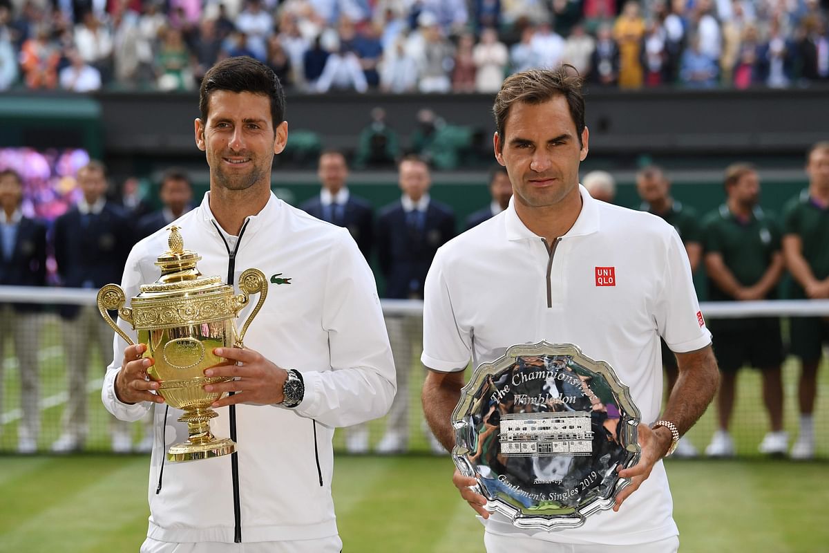 Serbia`s Novak Djokovic (L) poses with the winner`s trophy and Switzerland`s Roger Federer (R) holds the runners up plate during the presentation after the men`s singles final on day thirteen of the 2019 Wimbledon Championships at The All England Lawn Tennis Club in Wimbledon, southwest London, on July 14, 2019. AFP