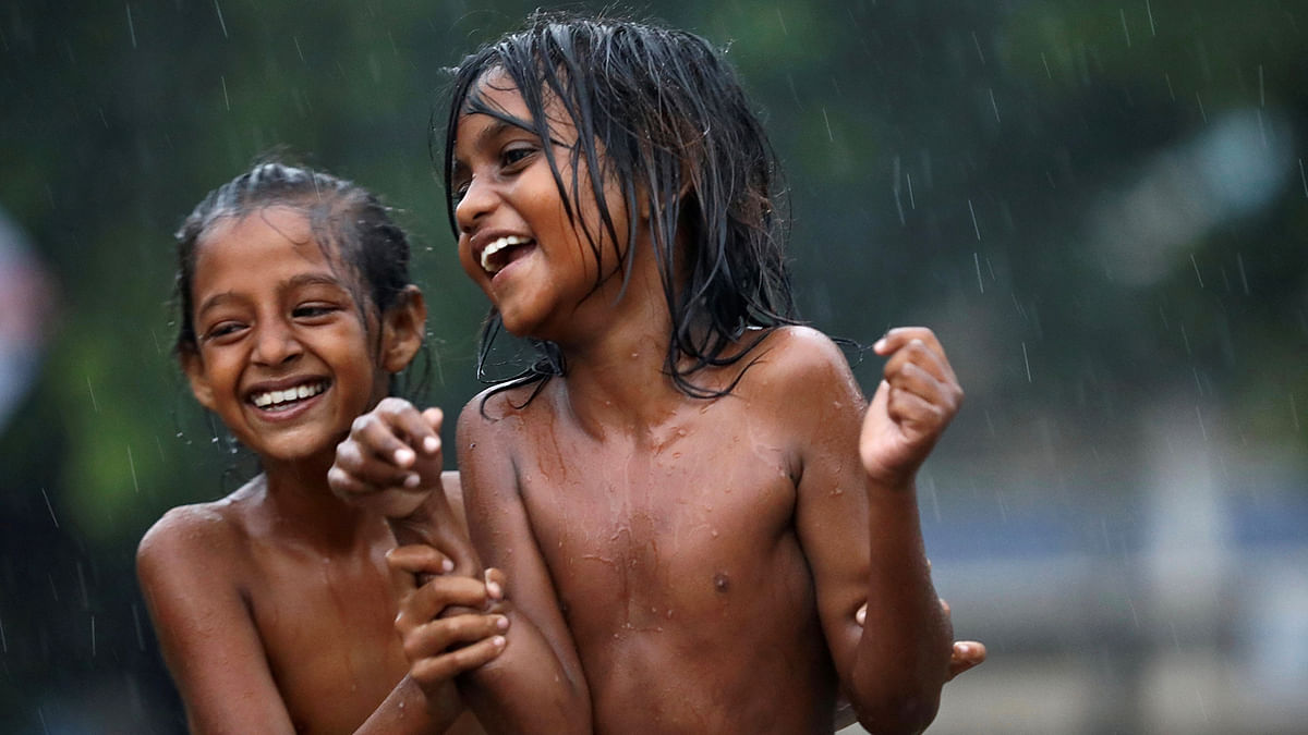 Children smile as they enjoy heavy rain in Dhaka, Bangladesh, 13 July, 2019. Photo: Reuters