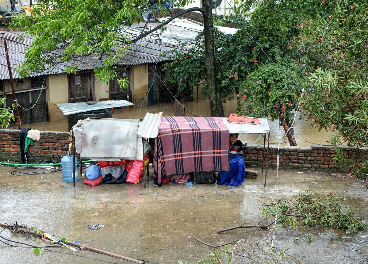 A Nepali resident takes shelter after the Balkhu River overflowed following monsoon rains at the Kalanki area of Kathmandu on 12 July 2019. Photo: AFP