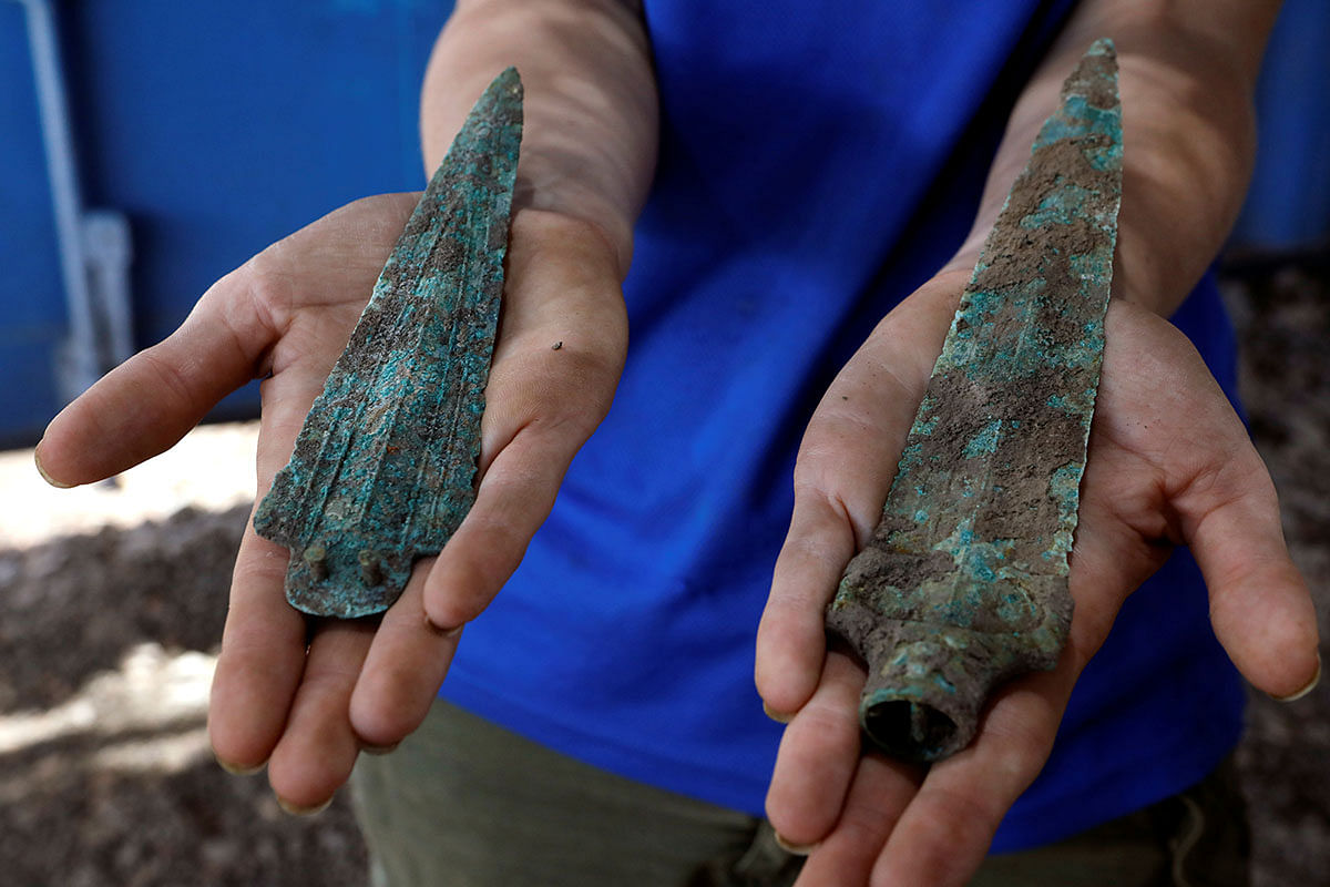 A woman holds an arrowhead and a dagger, part of findings uncovered at a huge prehistoric settlement discovered by Israeli archaeologists in the town of Motza near Jerusalem on 16 July 2019. Photo: Reuters