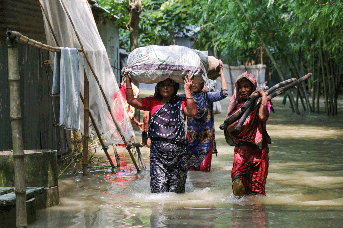 Bangladeshi women carry their belongings as they wade through flood waters following heavy mosoon rains in Kurigram on 17 July 2019. In flood-prone Bangladesh, which is criss-crossed by rivers, around one-third of the country is underwater and people were being killed by lightning strikes, officials said. Photo: AFP