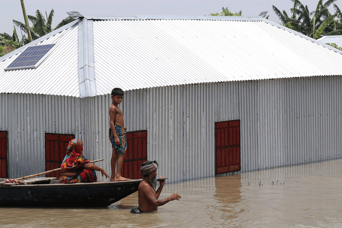 A Bangladeshi man pulls a canoe carrying his wife and son through flood waters following heavy mosoon rains in Kurigram on 17 July 2019. Photo: AFP