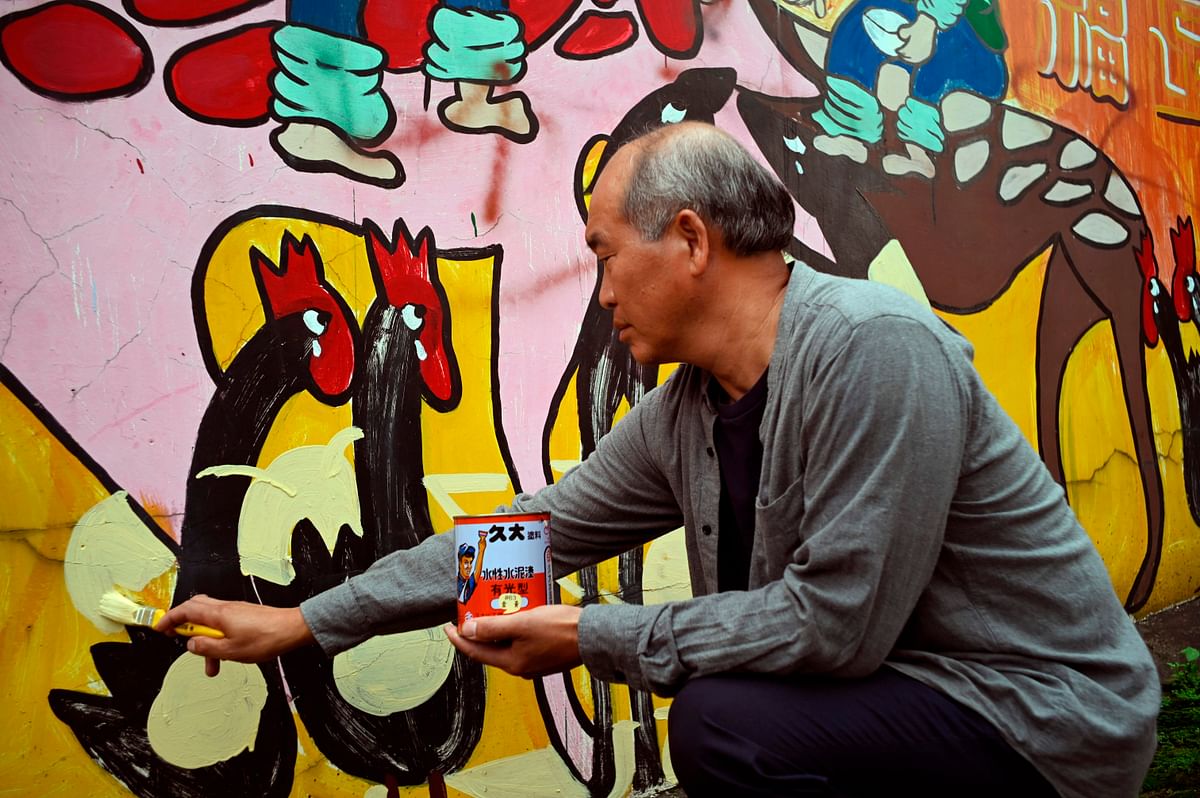 This picture taken on 21 May 2019 shows Hakka graffiti artist Wu Tsun-hsien painting a wall in the Taiwanese village of Ruan Chiao. Photo: AFP