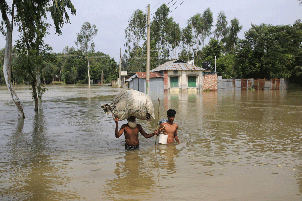 People move along a flooded area with their belongings in Gaibandha, Bangladesh, 19 July, 2019. Photo: Reuters