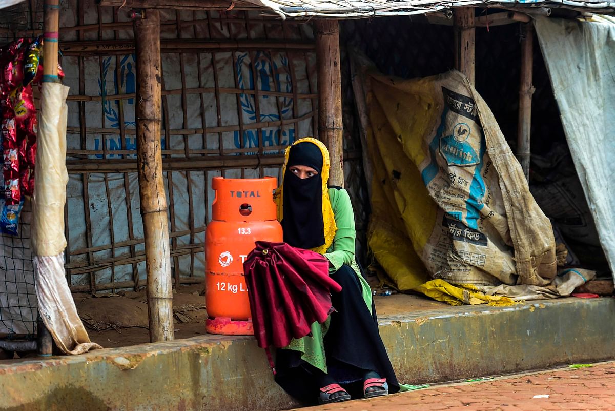 A Rohingya woman sits next to a petroleum gas cylinder as she waits for her relatives at Kutupalong refugee camp in Ukhia on 21 July, 2019. Photo: AFP
