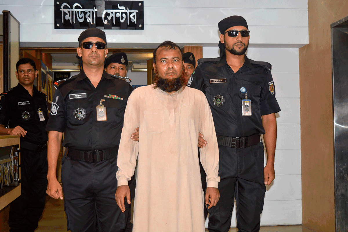 In this handout photo taken and released by the Bangladesh elite police Rapid Action Battalion (RAB) on 22 July 2019, officers escort Idris Ahmed (C), a cleric arrested for allegedly raping a dozen boys, in Dhaka on 22 July 2019. Photo: AFP