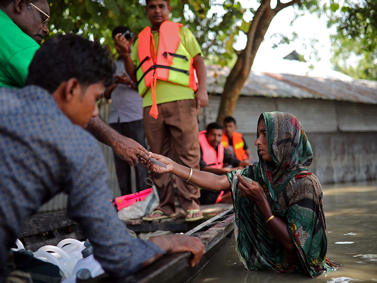 Flood-affected people receive water purifying tablets from volunteers in Jamalpur, Bangladesh, 21 July, 2019. Photo: Reuters