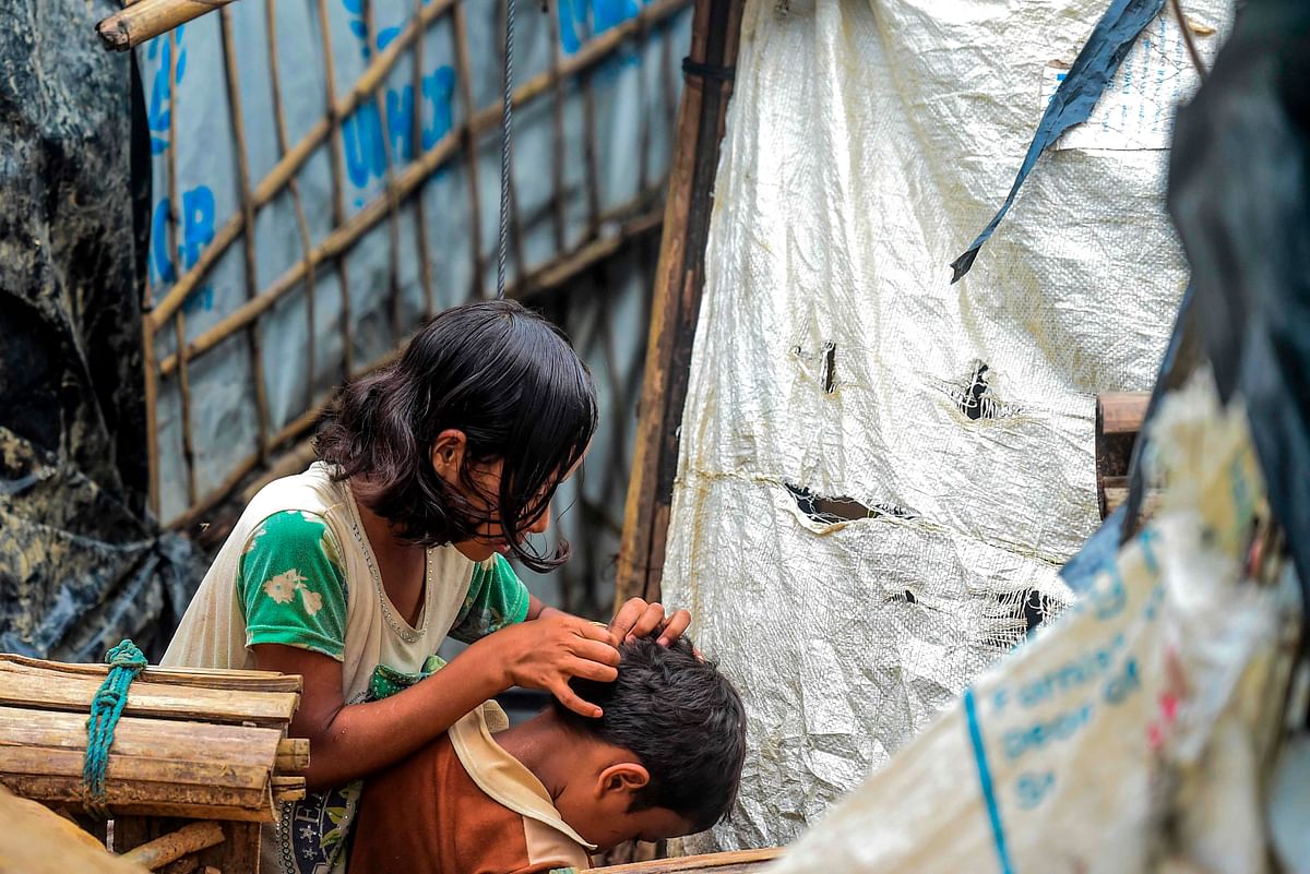 A Rohingya girl searches lice in her brother`s hair at Kutupalong refugee camp in Ukhia on 21 July, 2019. Photo: AFP