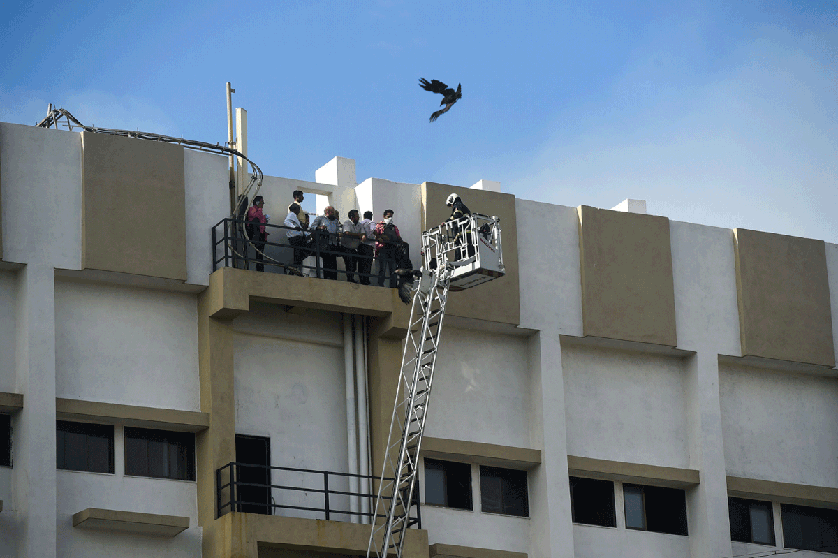 People are rescued by firefighters using a crane as they are trapped in a building caught on fire in Mumbai on 22 July 2019. Photo: AFP