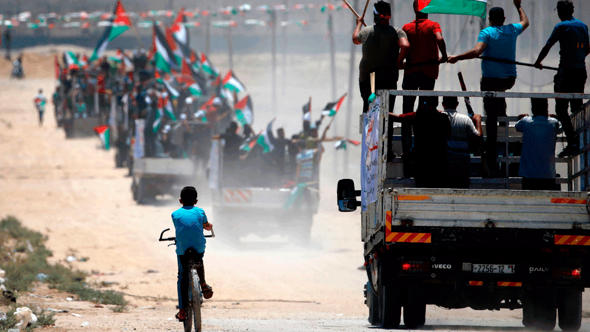 Palestinian demonstrators wave their national flag as they drive towards the border fence with Israel, east of Gaza City on 22 July, 2019. Photo: AFP