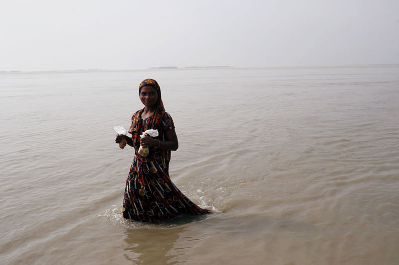 A flood-affected woman wades through flooded area in Jamalpur, Bangladesh on 21 July 2019. Photo: Reuters