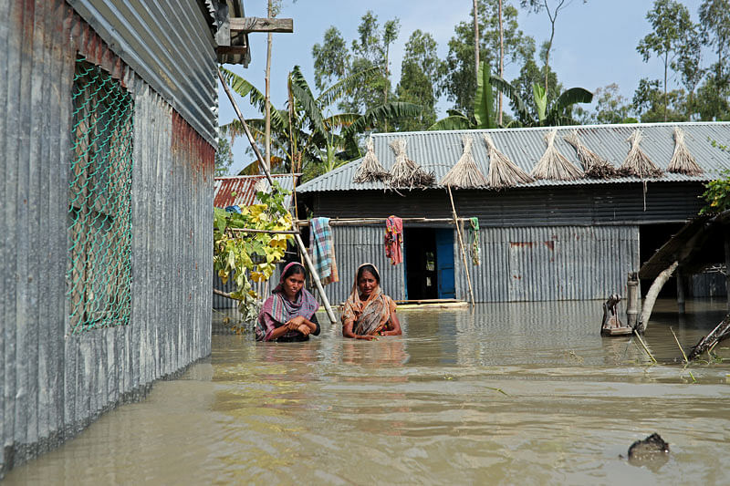 Flood-affected women are seen standing in chest-deep water in front of their house in Jamalpur, Bangladesh, on 21 July 2019. Photo: Reuters