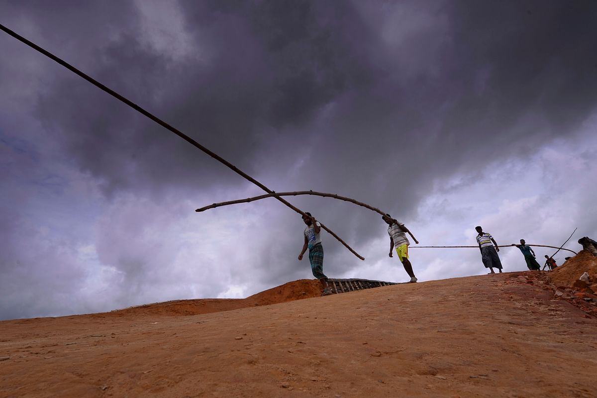 Rohingya refugee men carry bamboo poles at Kutupalong refugee camp in Ukhia on 23 July 2019. Photo: AFP