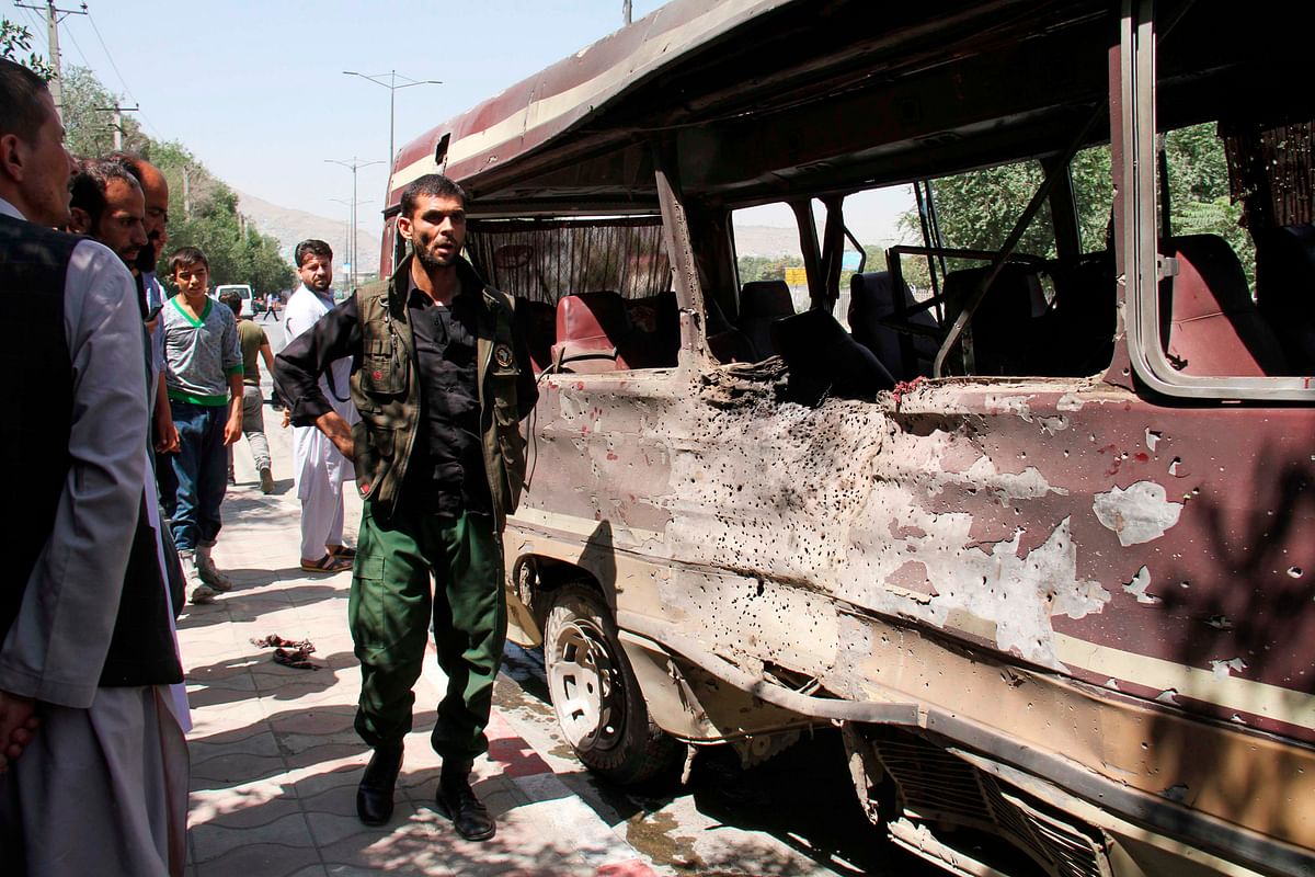 Afghan security personnel and residents look at the wreckage of a bus following a suicide bombing in Kabul on 25 July 2019. Photo: AFP