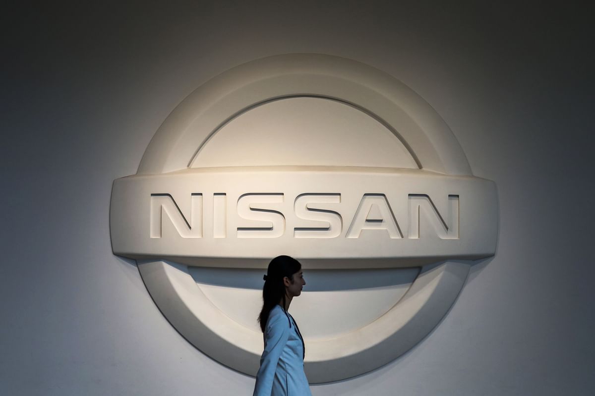 This file photo taken on 14 May 2019 shows a woman walking past a logo of Nissan Motors at the company`s headquarters in Yokohama. Photo: AFP