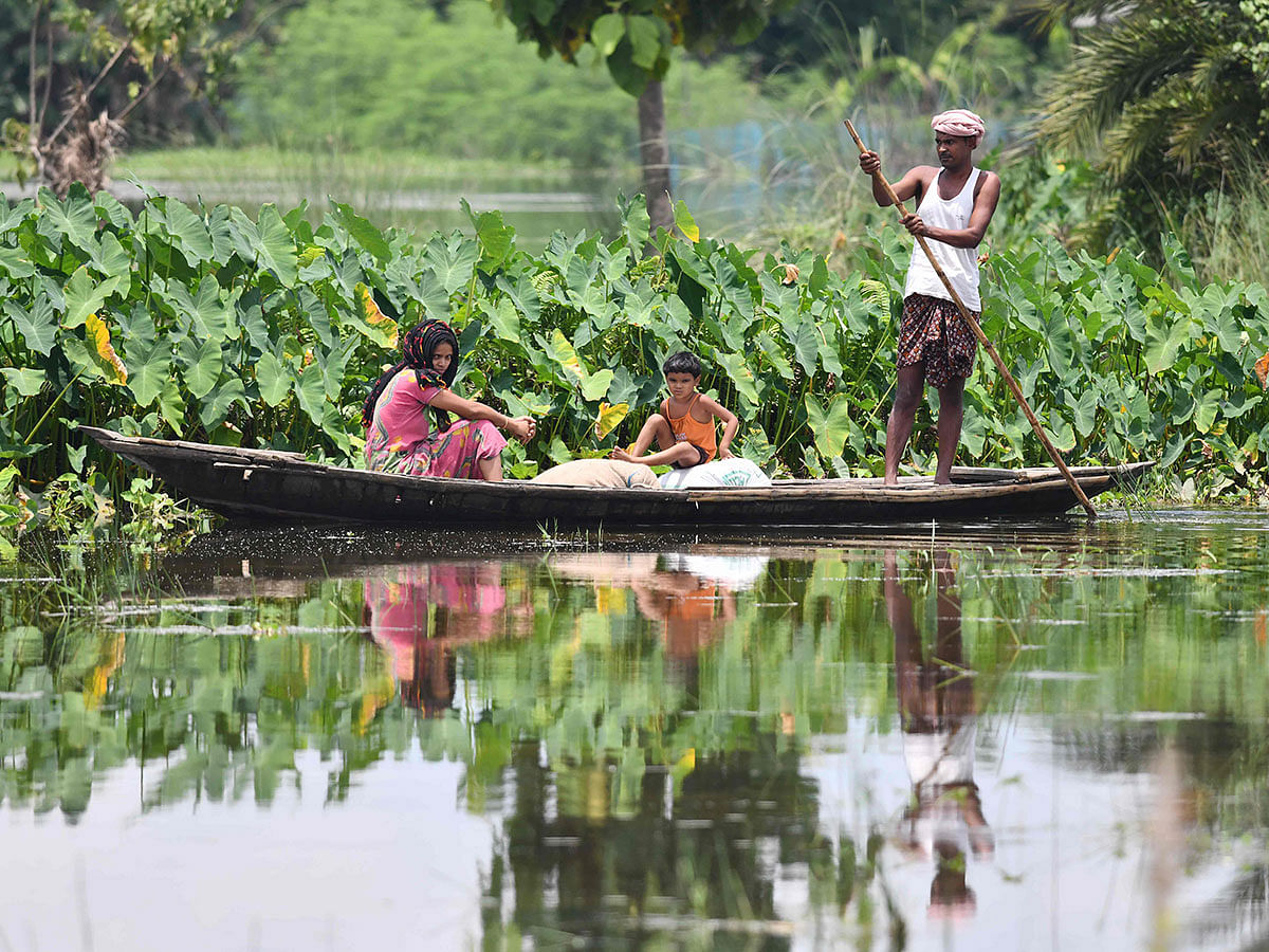 Villagers travel on a boat in flood waters at the flood affected area of Sarukhetri village in Barpeta district of Assam, on 25 July 2019. Photo: AFP
