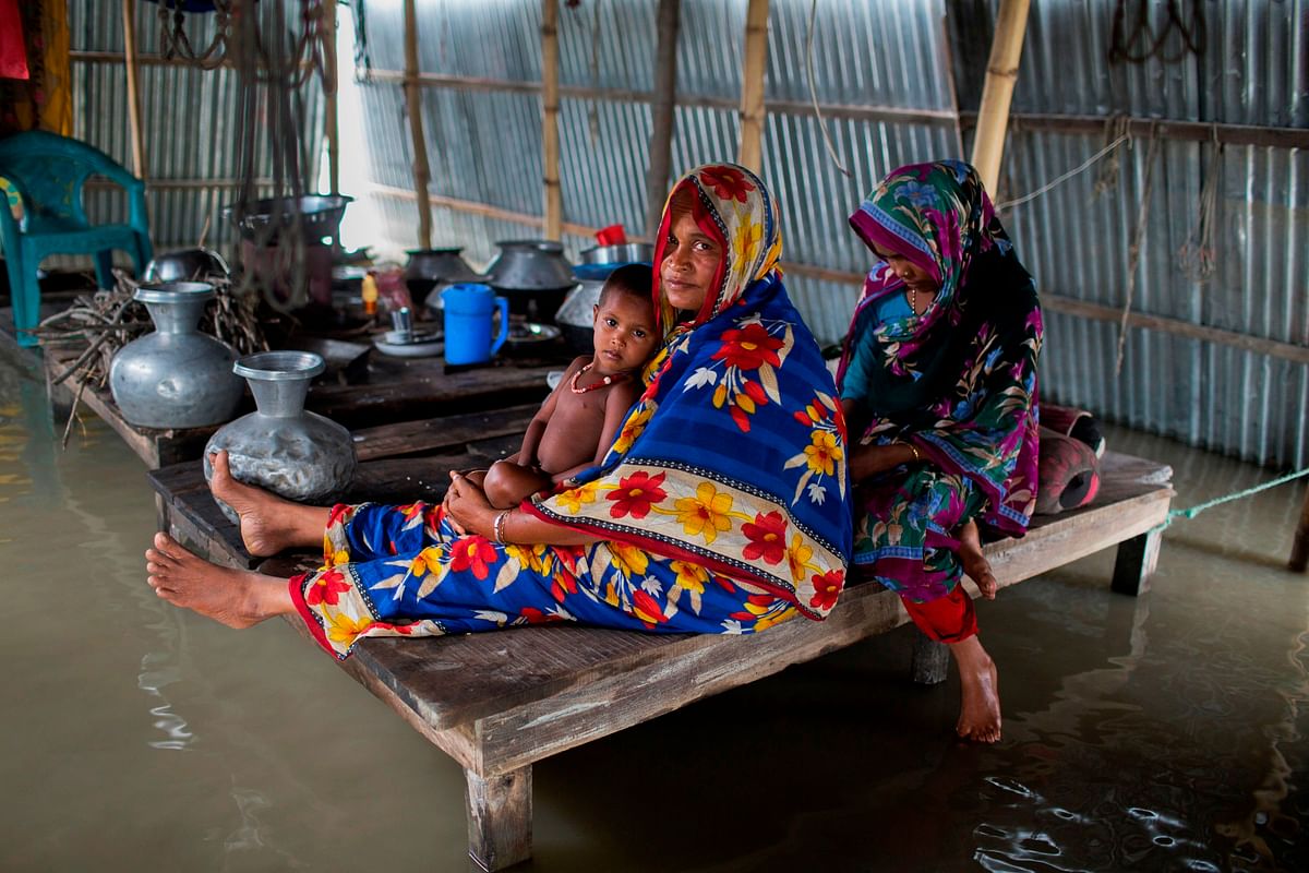 A flood-affected family rests inside their flooded house in Kurigram on 26 July 2019. The death toll from monsoon storms in Bangladesh rose above 100 on 26 July with flood levels still rising in many parts of the country, officials said. Photo: AFP