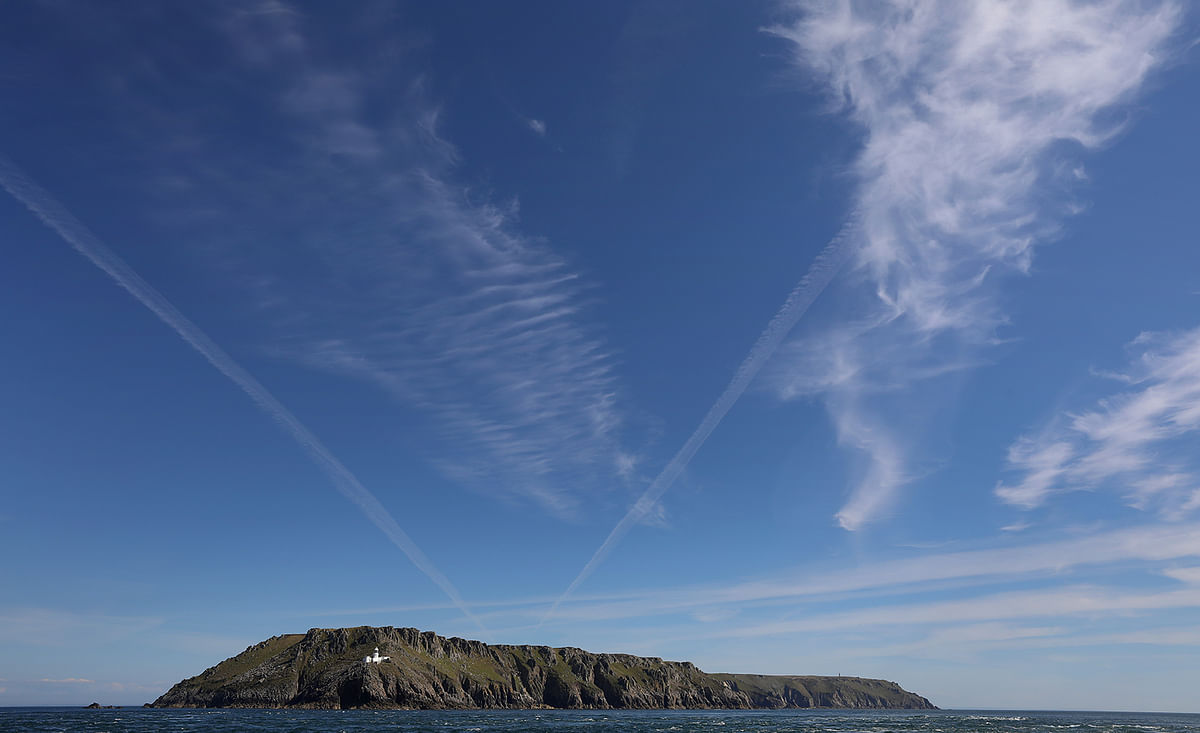 Cirrus clouds and contrails are seen above the island of Lundy and its `North Light` lighthouse during the gathering of the Cloud Appreciation Society on Lundy. Photo: Reuters