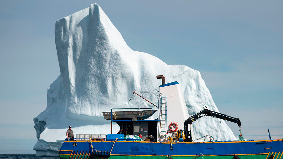 Captain Edward Kean stands on his boat in front of an iceberg in Bonavista Bay on 29 June 2019 in Newfoundland, Canada. Photo: AFP