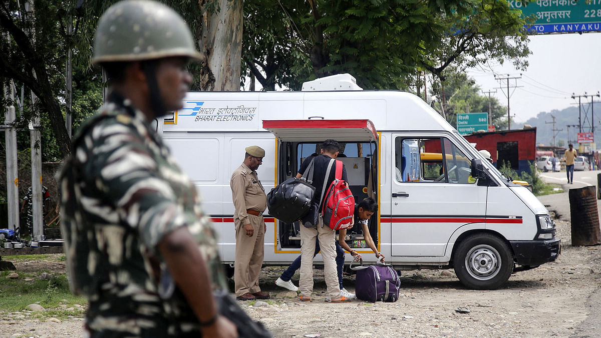 An Indian security forces personnel stands guard as Jammu Kashmir police men check the luggage and vehicles of commuters on the Jammu-Srinagar National highway at Nagrota some 25 kms from Jammu on 2 August, 2019. Photo: AFP