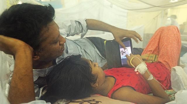 A father spends time with his dengue affected child at Chittagong Medical College, Chittagong on 2 August 2019. Photo: Jewel Shil