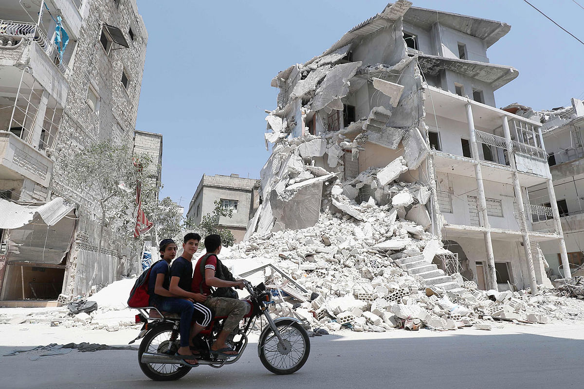 A Syrian man drives a motorcycle past destroyed buildings in the town of Ariha, in the south of Syria`s Idlib province, on 2 August. Photo: AFP