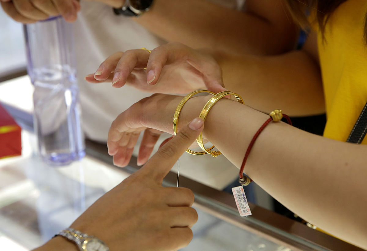 A customer tries on gold bracelets at Caibai Jewelry store in Beijing. Photo: AFP
