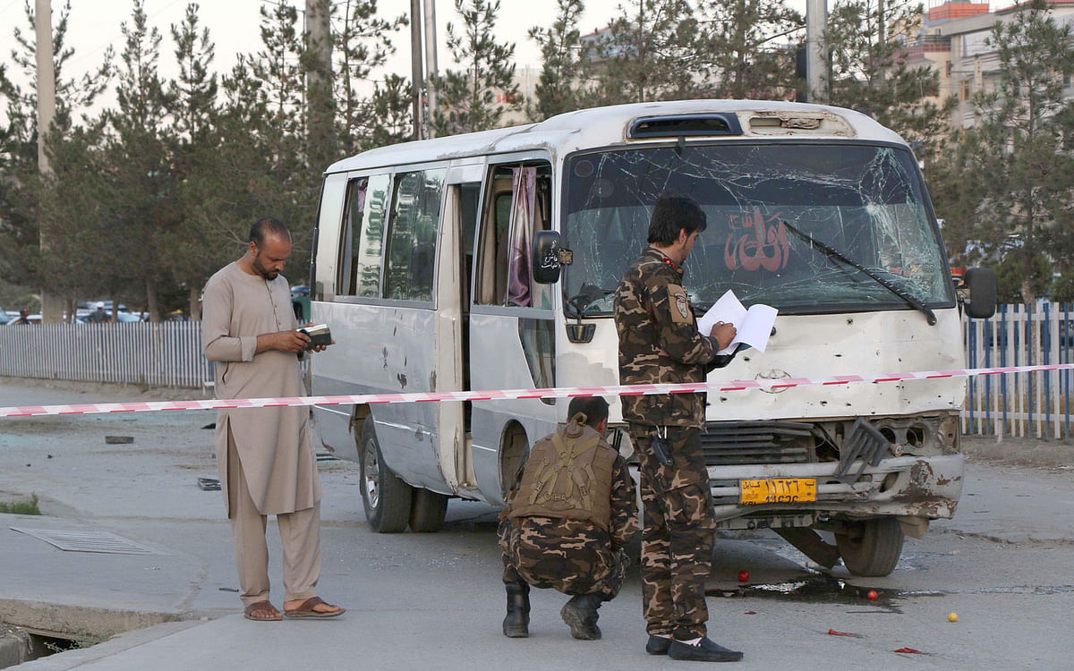 Afghan security personnel investigate a damage bus carrying employees of Khurshid TV, at the site of a sticky bomb blast in Kabul on 4 August. Photo: AFP