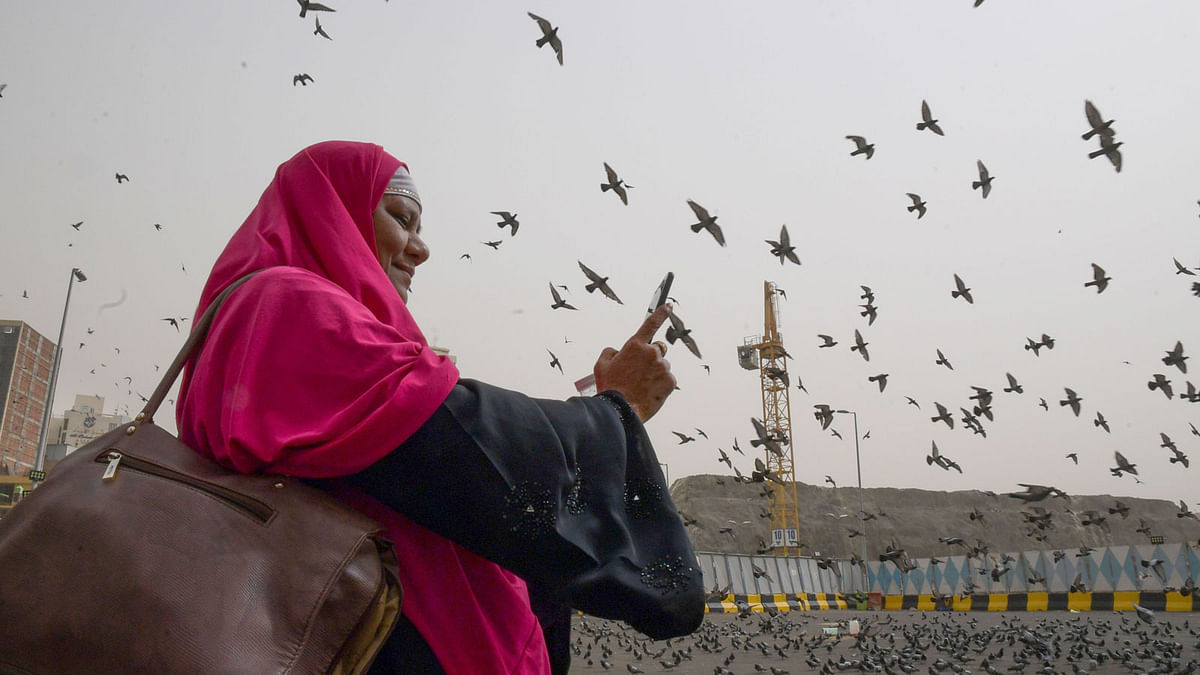 A Muslim pilgrim snaps pictures of pigeons as she walks in the streets of the Saudi holy city of Mecca on 6 August 2019, a few days ahead of the annual Hajj pilgrimage. Photo: AFP