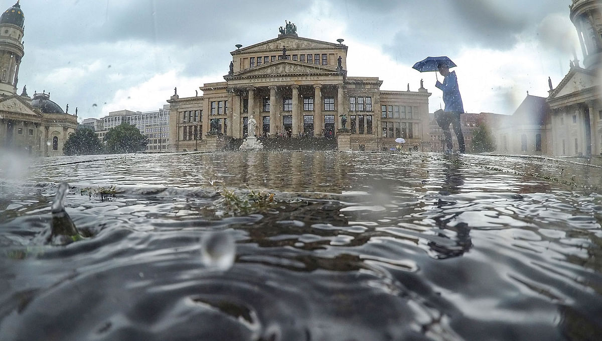 A heavy rain shower falls on Gendarmenmarkt square with the Konzerthaus (C, Berlin concert hall), the Deutscher Dom (L, German Church) and the Franzoesischer Dom (R, French Church) on 7 August, 2019 in Berlin, Germany. Photo: AFP