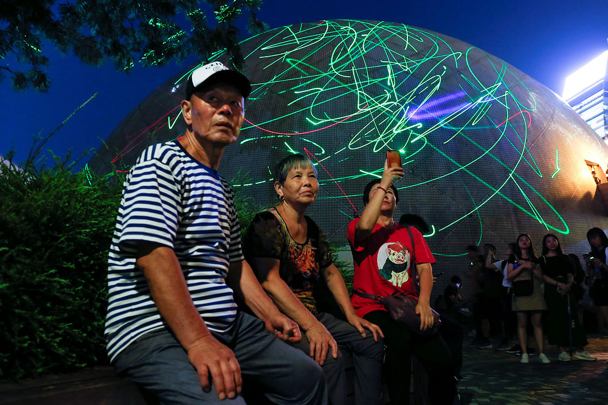 People watch the dots of laser pointers move across buildings in front of the Hong Kong Space Museum during a flash mob staged to denounce the authorities` claim that laser pointers were offensive weapons in Hong Kong, China on 7 August. Photo: Reuters