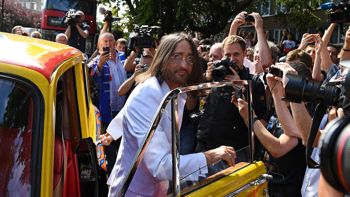 Beatles lookalike band `Fab Gear` member John Lennon gets out of his replica psychedelic rolls royce car to join fans at the famous Abbey Road zebra crossing in London, England on 8 August, 2019, on the 50th anniversary of the day that the iconic Beatles album cover photograph was taken. Photo: AFP