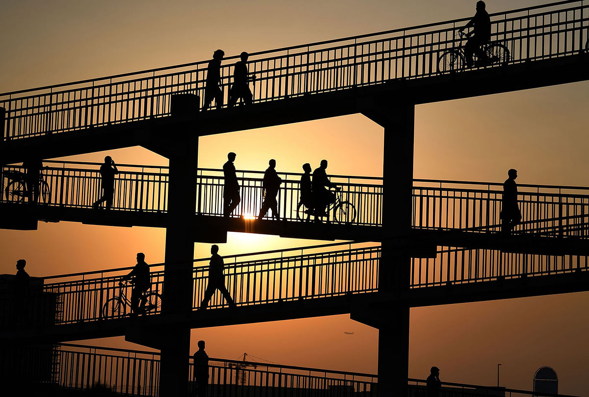 Asian labourers cross a pedestrian bridge in Dubai on 7 August 2019, as they head to work at a vegetable market. Photo: AFP