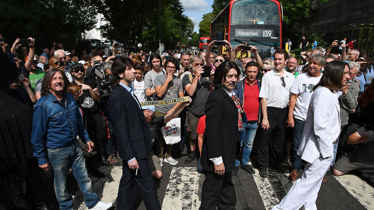 Beatles lookalike band `Fab Gear` and fans of The Beatles pose at the famous Abbey Road zebra crossing in London, England on 8 August, 2019, the 50th anniversary of the day that the iconic Beatles album cover photograph was taken. Photo: AFP