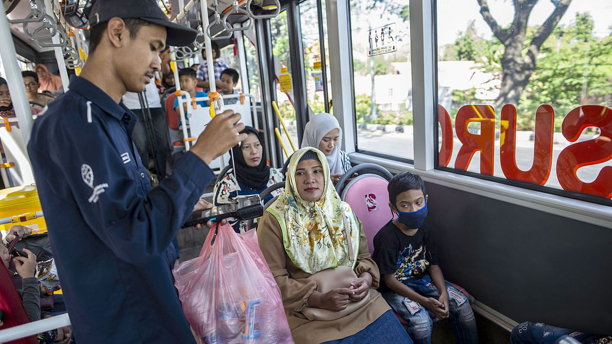 This picture taken on 21 July 2019 shows a bus conductor collecting used plastic bottles as fare payment on board a Suroboyo bus in the Indonesian city of Surabaya. Photo: AFP