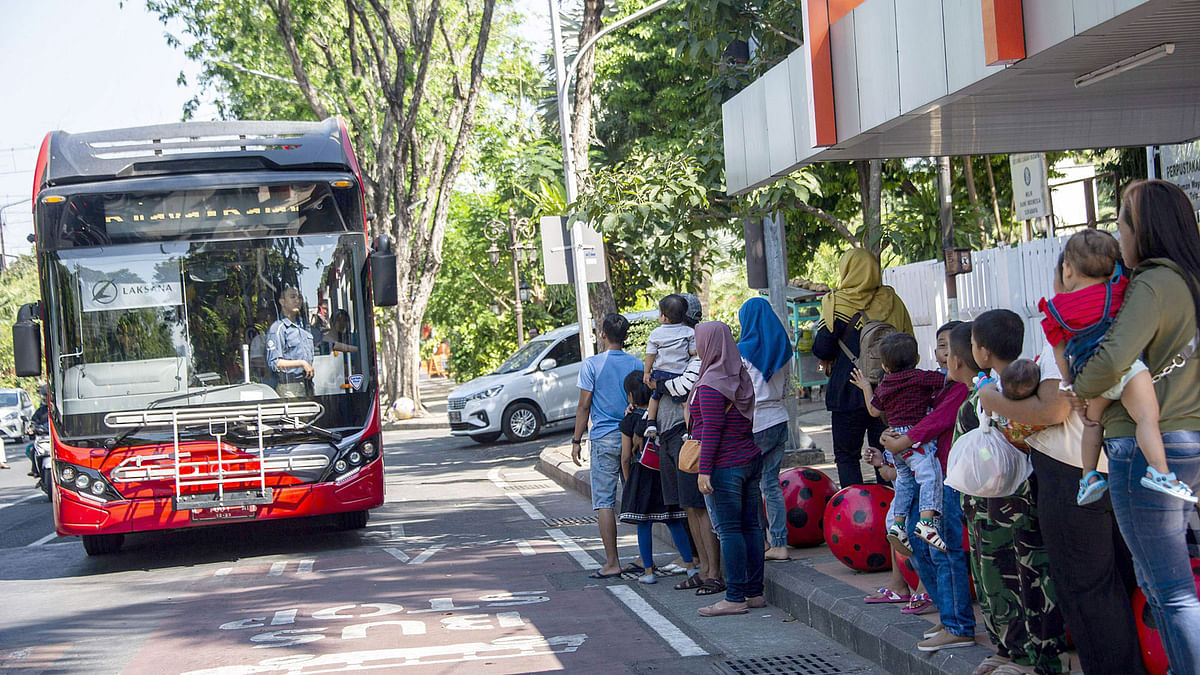 This picture taken on 21 July 2019 shows commuters, some clutching bags full of plastic bottles and disposable cups to be used as bus fare, waiting at a bus terminal in the Indonesian city of Surabaya. Photo: AFP