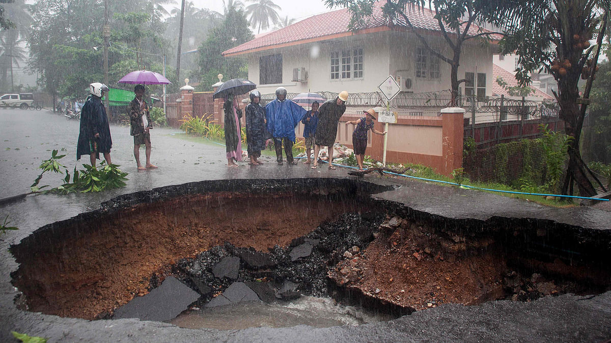 People look at a hole in a road caused after flooding in Mawlamyein, Mon state in Myanmar on 9 August 2019. Photo: AFP