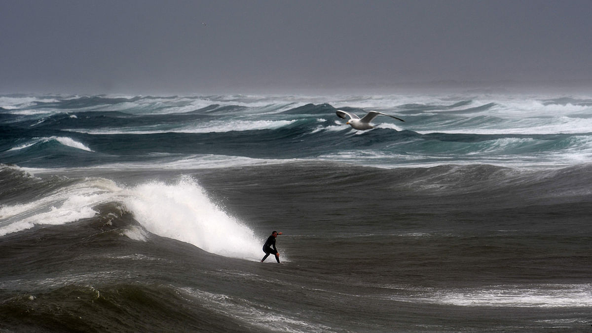 A man surfs a wave on 9 August 2019 at the Pointe-de-la-Torche in Plomeur, western France as strong winds hit the coast. Photo: AFP