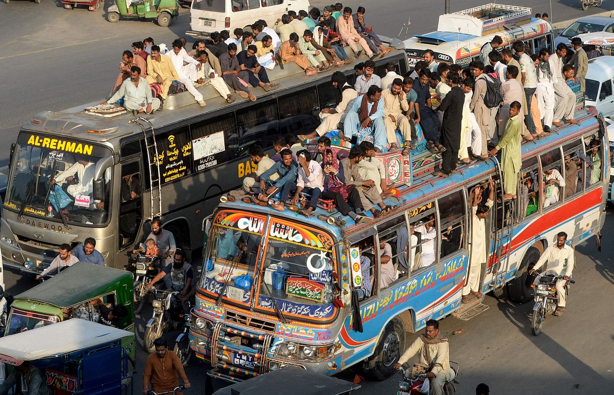 Travelers sit on buses to go back home to be with their families on the eve of the Muslim festival of Eid al-Adha, at a railway station in Lahore on 10 August 2019. Photo: AFP