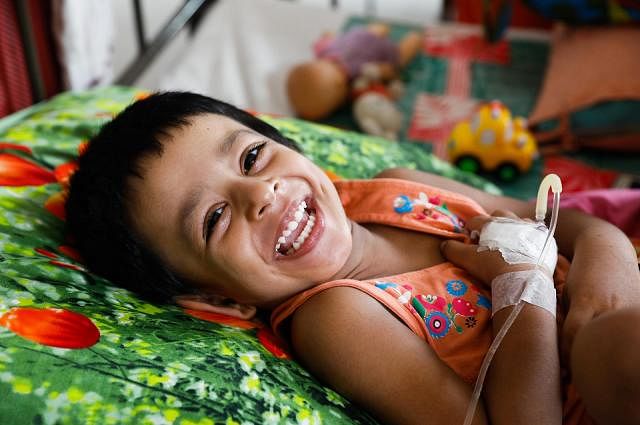 2 year and 9 month-old girl Ariba, hospitalised in a Dhaka hospital with dengue fever, smiles after getting her Eid dress on 12 August, 2019. Photo: Dipu Malakar