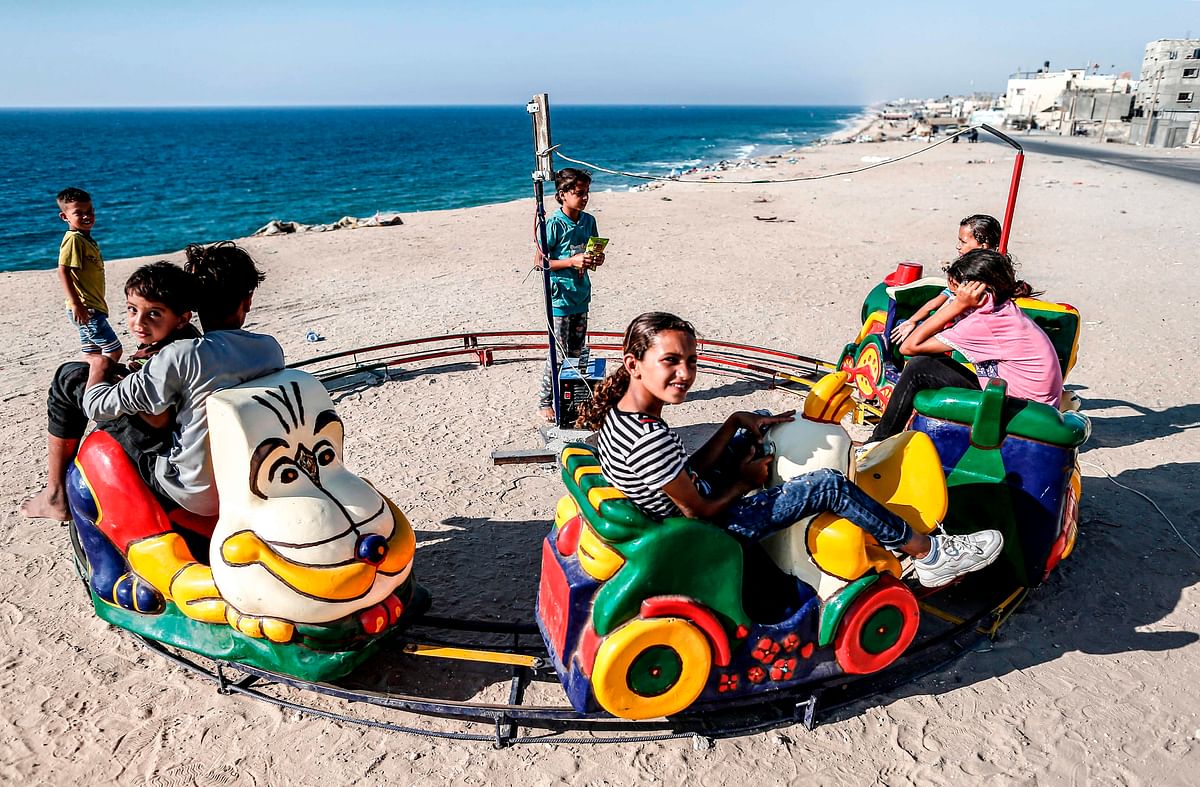 Palestinian children ride on a toy train overlooking the Mediterranean, while celebrating during the third day of the Muslim religious festival of Eid al-Adha in the Deir al-Balah refugee camp in the central Gaza Strip on 13 August 2019. Photo: AFP